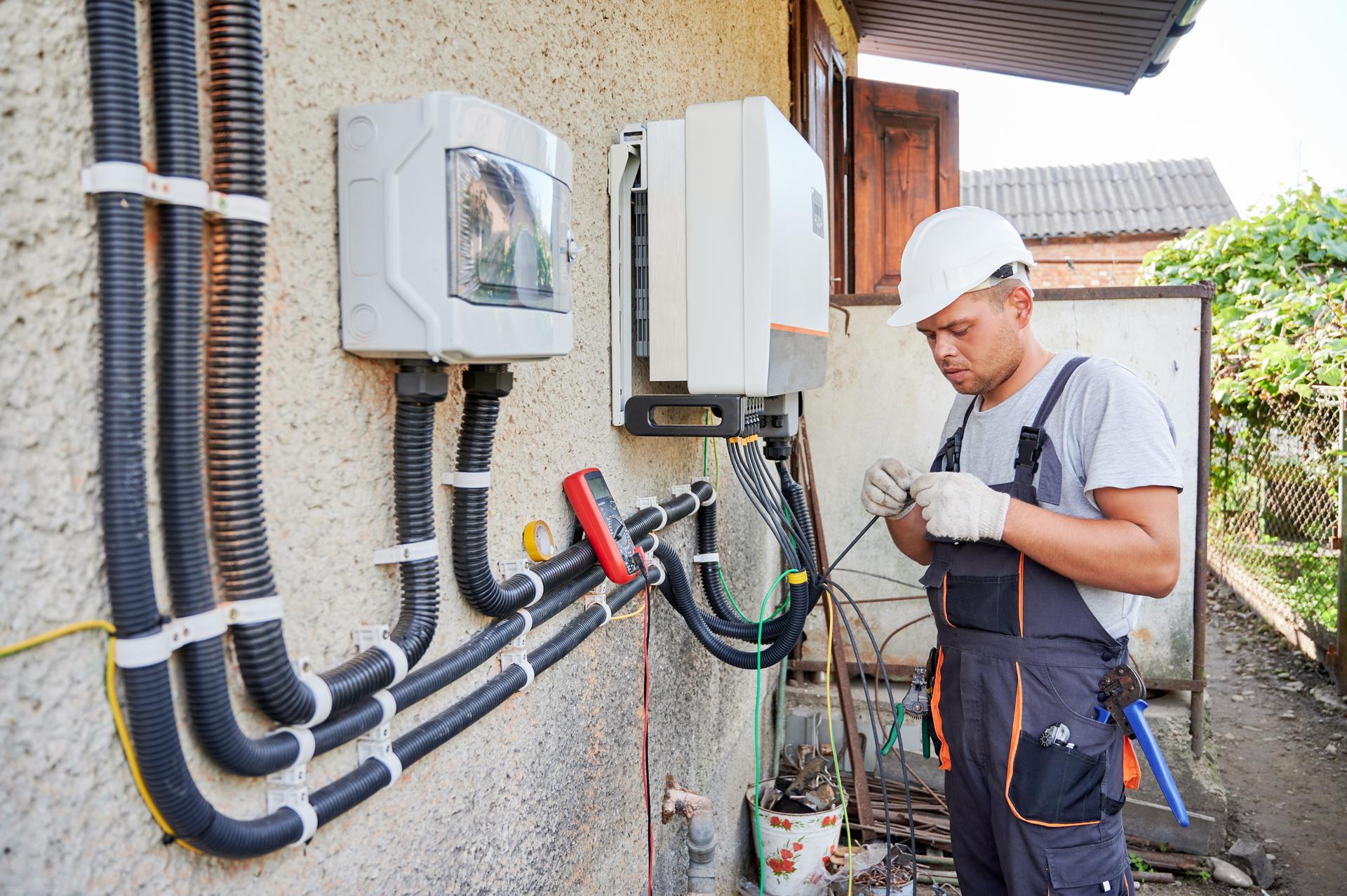 Electrician installing solar panel system, wiring inverter and electric box